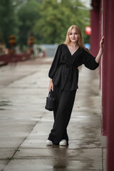 Portrait of a young beautiful blonde girl in dark clothes outdoors.