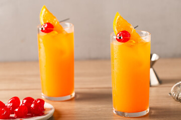Homemade Tequila Sunrise Cocktail refreshment tequila, fresh orange juice, fresh lime juice and grenadine garnish with an orange slice and a cherry
