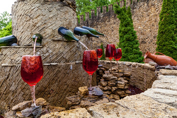 Fountain with red wine pouring from bottles