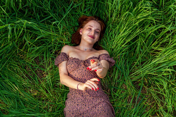 A young girl in a beautiful dress lies in the green grass