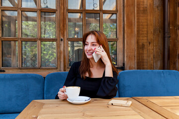 A girl in a cafe at a table talking on the phone