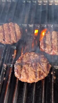 steak bbq burger patties fry over an open fire on the grate flip flame spills on the sides in real time next to foil 