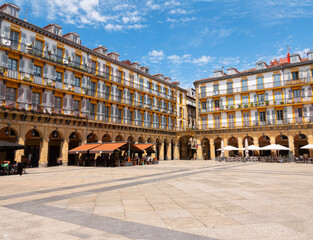 Fototapeta na wymiar View of the Plaza de la Constitucion (Constitution Square) in heart of San Sebastian Old Town, Spain. Rectangular shape and surrounded by 4-storey arcaded buildings. Blue sky background.
