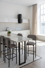 kitchen and dining island with high bar stools in a minimalistic modern luxury design of an expensive house on a sunny day. white walls with plaster, parquet, decorative lighting and no one inside