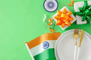 Republic Day India festivities concept. Top view photo of plates, cutlery, national flag, ashoka wheel, patriotic gift boxes, sparkles on light green background with blank space for advert or text