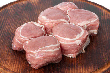 Raw meat medallions on a wooden board.