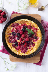 Omelette with berries in pan on wooden table