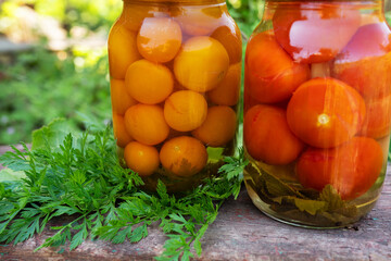 Tomatoes yellow and red in a jar, the process of harvesting for the winter. Close-up, jars outside on a wooden chair.