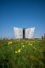 The Beautiful Exterior of the Titanic Museum in Titanic Quarter with beautiful yellow tiny flowers view in its front - obrazy, fototapety, plakaty