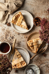 Three plates with traditional apple pie pieces served for an autumn cozy tea party. Rustic stil life, brown textured background. Autumn seasonal food concept, top view