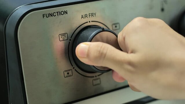 A hand turns the function knob of a microwave oven that has an air fry function. Taken with a medium shot and handheld.