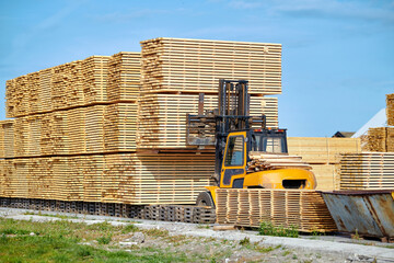 Forklift loading lumber wood boards in stack, finished product warehouse ready for transportation....
