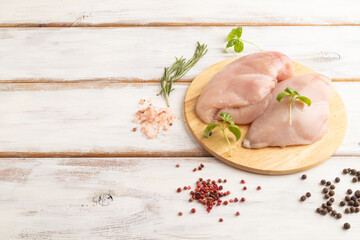 Raw chicken breast on white wooden background. Side view, copy space.