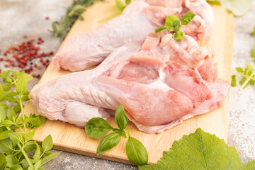 Raw turkey wing on a wooden cutting board on a brown concrete background. Side view, selective focus