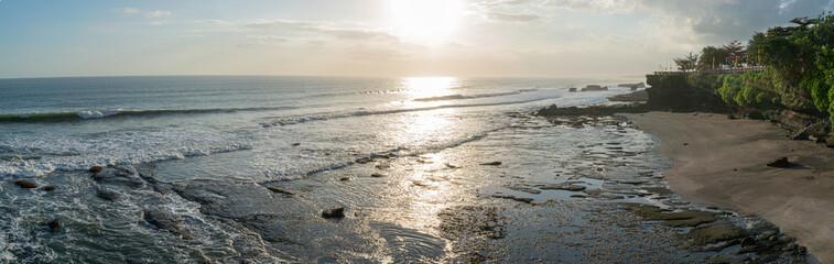 Panoramic view of the horizon of a coral beach with waves chasing in the bright afternoon sun