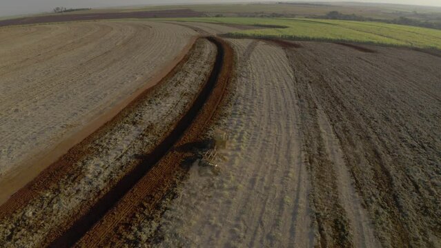 tractor plowing and mixing products to the ground for future sugarcane plantation at sunset