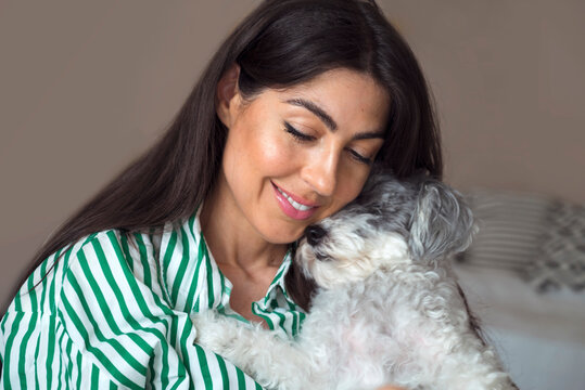 Beautiful Young Woman Hugging her White Senior Havanese Dog at Home 