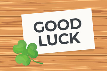good luck written on the paper card and green clover on wooden table - vector illustration