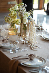 beautiful table setting with flowers and cutlery on wooden table at wedding or dinner. stylish tablewear decorations