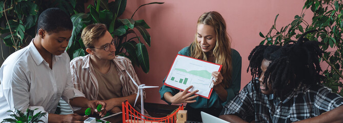 Diverse group of international students working on the urban project of modern city with renewable energy source, green areas. Concept of ecology, environment, waste recycling, technology banner
