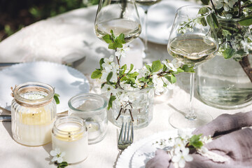 Rustic elegant eco friendly zero waste trendy wedding reception table decor with fresh spring apple cherry flowers in bloom. Beautiful marriage decoration, holiday event outdoors in the family garden