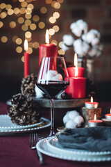 Rustic table decor for Christmas or New Year family dinner. Centrepiece with red candle, dry orange, cone, cinnamon, anise. Zero waste eco-friendly home. Cozy atmosphere, dark background. Close up