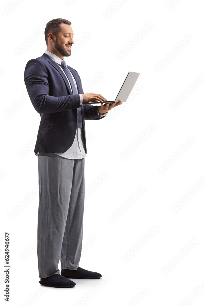 Sticker Full length shot of a man wearing a suit and bottom pajamas and working on a laptop computer