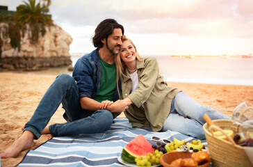 Happy romantic couple relaxing together on outdoor picnic at beach