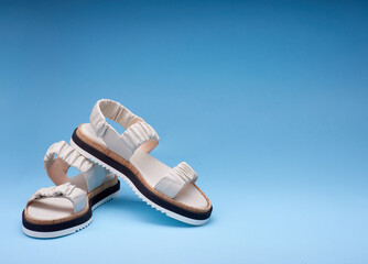 Naklejka premium A shot of new pastel leather sandals with three-colored soles placed one on another. Gradient blue background. Concept of selling shoes