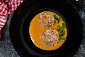 meatballs in sauce on a black plate.