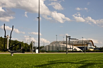 Obraz premium Przyrządy siłowni zewnętrznej na tle innych obiektów sportowych i boisk w słoneczny dzień