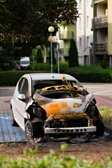 Rozbity i spalony przód auta stojący na parkingu na osiedlu - obrazy, fototapety, plakaty
