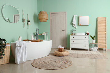 Obraz na płótnie Canvas Interior of bathroom with bathtub, mirrors and chest of drawers