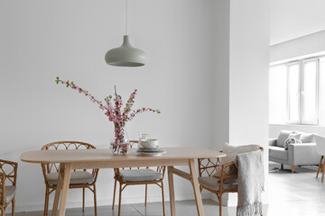 Interior of stylish dining room with blooming sakura branches on table