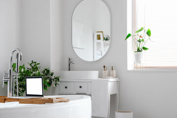 Interior of light bathroom with bathtub, dressing table and mirror