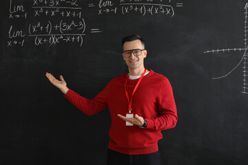 Male Math teacher conducting lesson near blackboard in classroom
