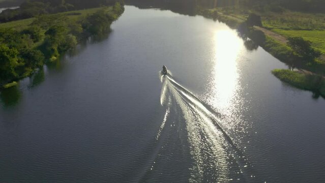 small motor boat sailing on the Tiete River at sunset