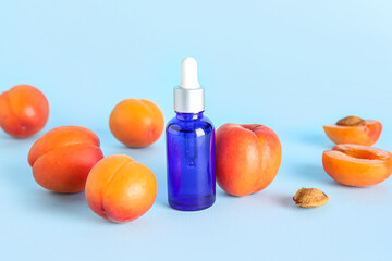 Bottle of essential oil and ripe apricots on color background