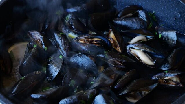 cooking, mussels with garlic and lemon in a frying pan, close up