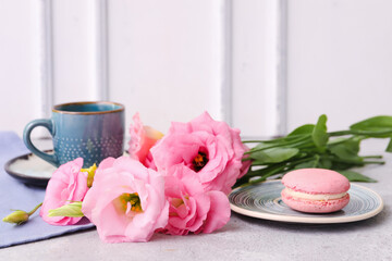 Obraz na płótnie Canvas Beautiful pink eustoma flowers, plate with macaroon and cup of coffee on white table