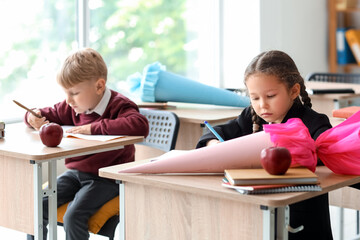 Classmates with school cones sitting at desks in classroom