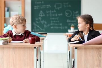 Classmates with school cones sitting at desks in classroom