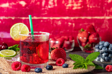 Berry drink with fresh blueberries, strawberries, cherries and raspberries, berry ice lemonade in a glass