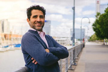 Middle-aged Latin man businessman with his arms crossed looks at the camera smiling, copy space