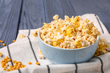 Bowl with tasty popcorn on blue wooden background