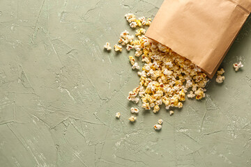 Paper bag with tasty popcorn on grey background
