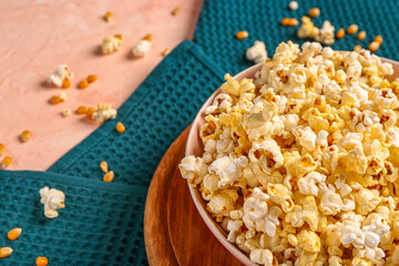 Bowl with tasty popcorn and seeds on pink background