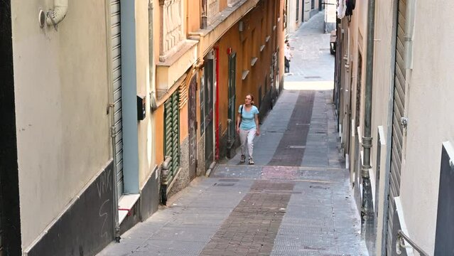 Genoa, Liguria, Italy. 3 june 2023. Fascinating footage of an alley in the historic centre, called caruggio in the local language. A middle-aged woman explores it, discovering glimpses of Genoa.