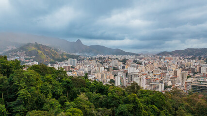 Fototapeta na wymiar Aerial view of Rio de Janeiro on a cloudy day, in the neighborhoods of Tijuca and adjacencies and green areas such as the Tijuca National Park. In the background, Maracanã stadium and Guanabara Bay.