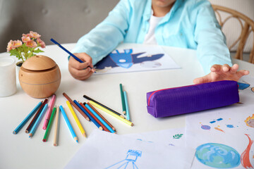 Little African-American boy with pencil case drawing at home, closeup